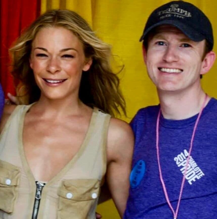Photo of Paul Kelly with LeAnn Rhimes posed before a curtain
