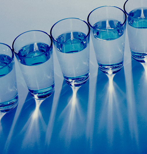 A photo of glasses of water in a diagonal row and seen from above.