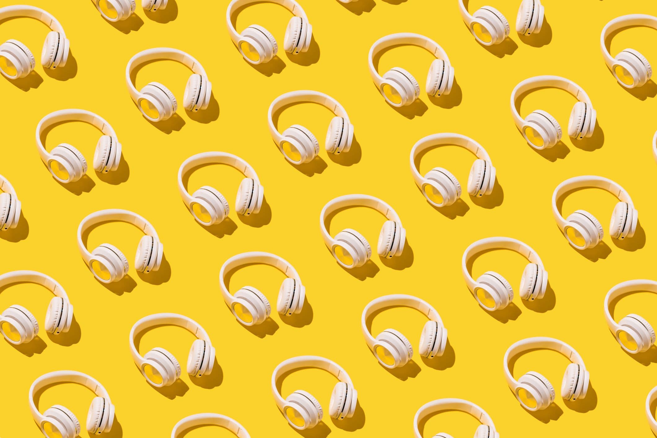An image of headphones in diagonal rows against a bright yellow field.
