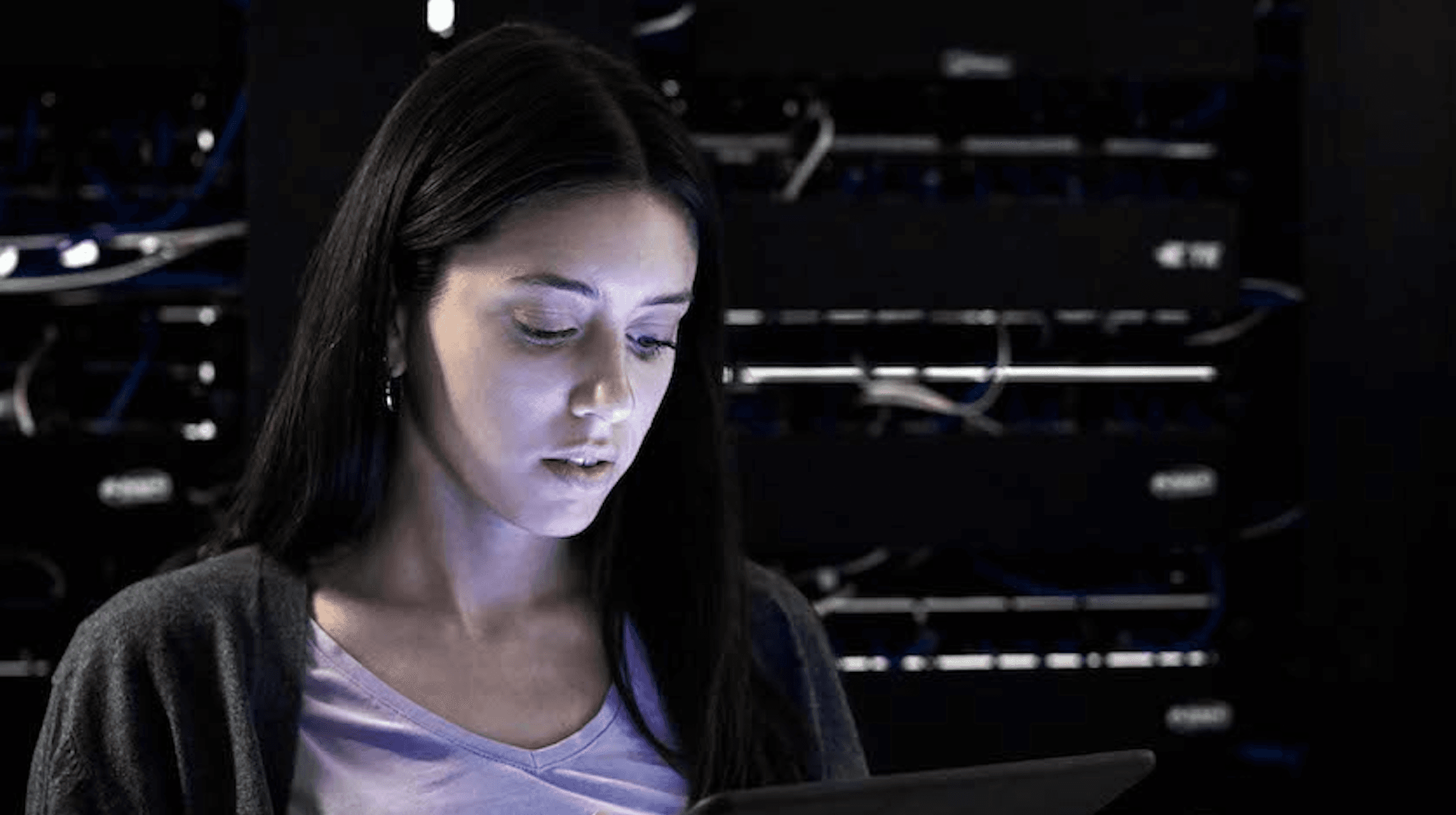 Photo of a young woman with long dark hair looking down at a laptop.